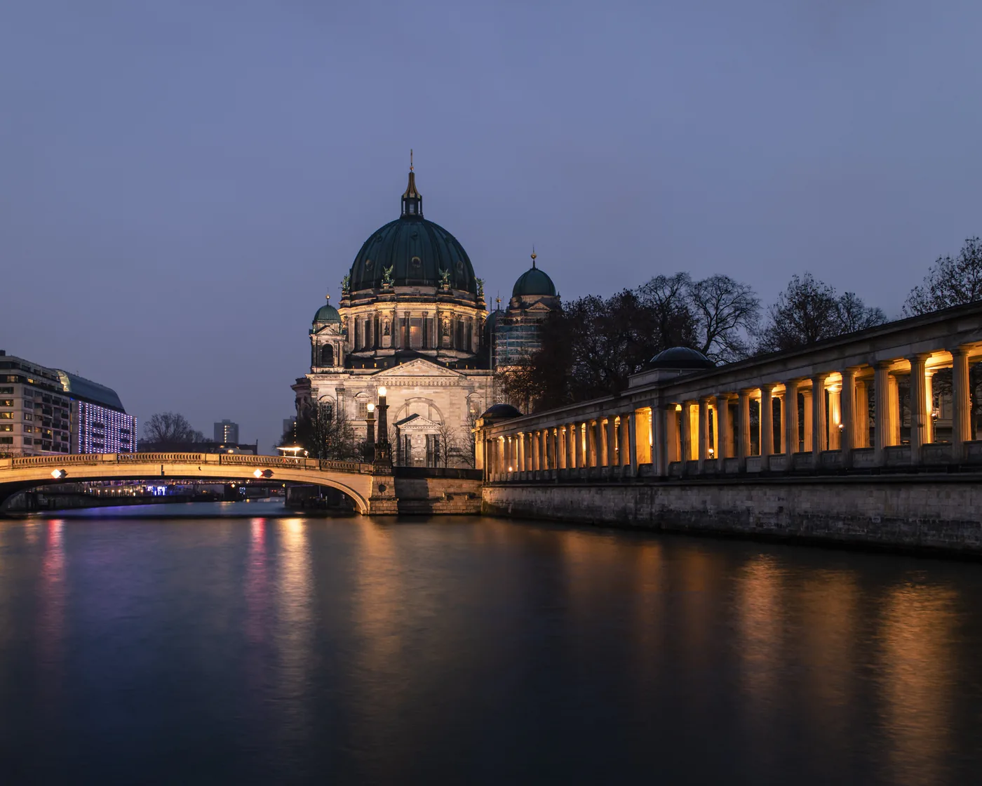 The Berliner Dom across the Spree at dusk, with the museum colonnade lit along the far bank